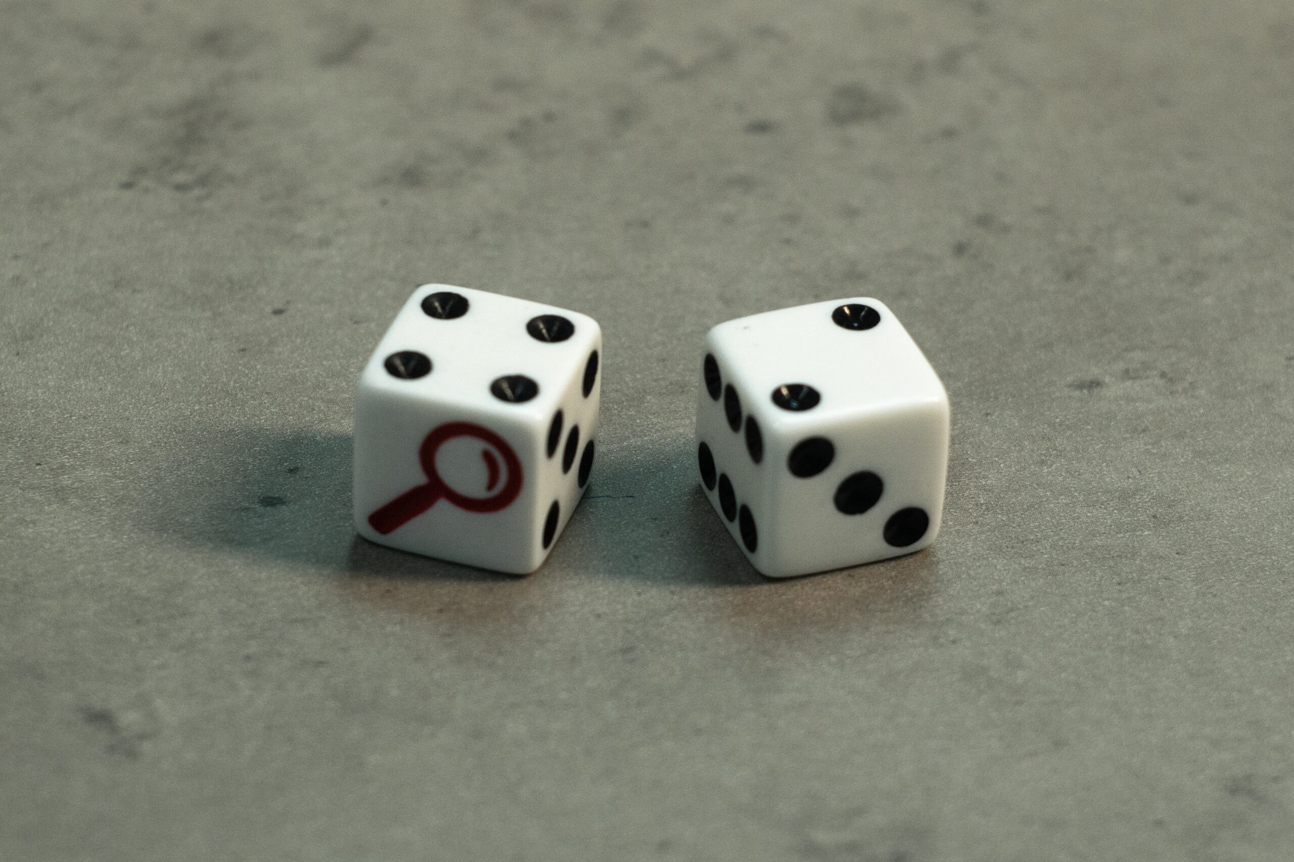 two dice, one of which has a magnifying glass on it