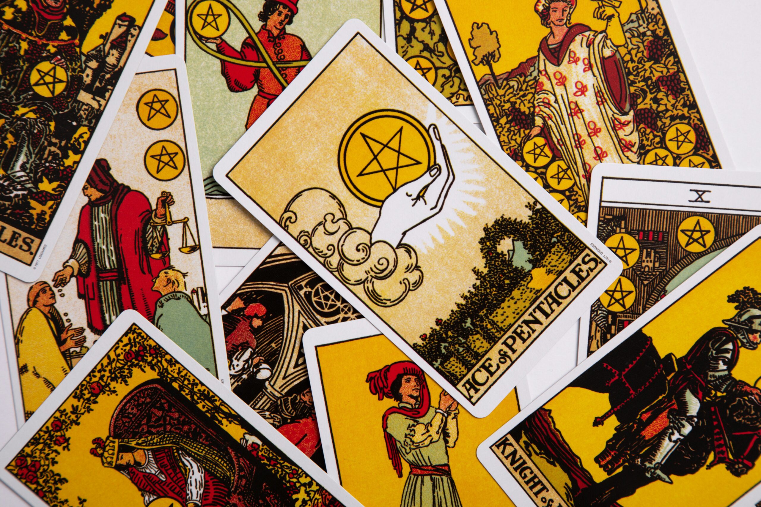 overlapping tarot cards with the Ace of Pentacles, showing a spirit hand holding a pentagram, on top