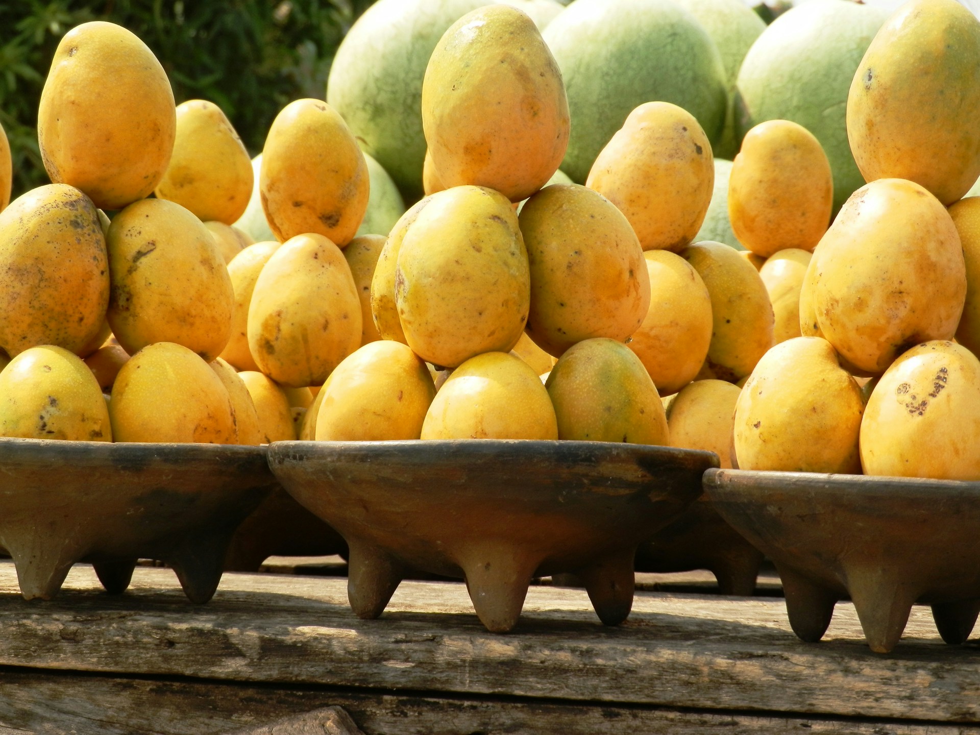 towers of mangos, each tower in a wooden bowl on a table